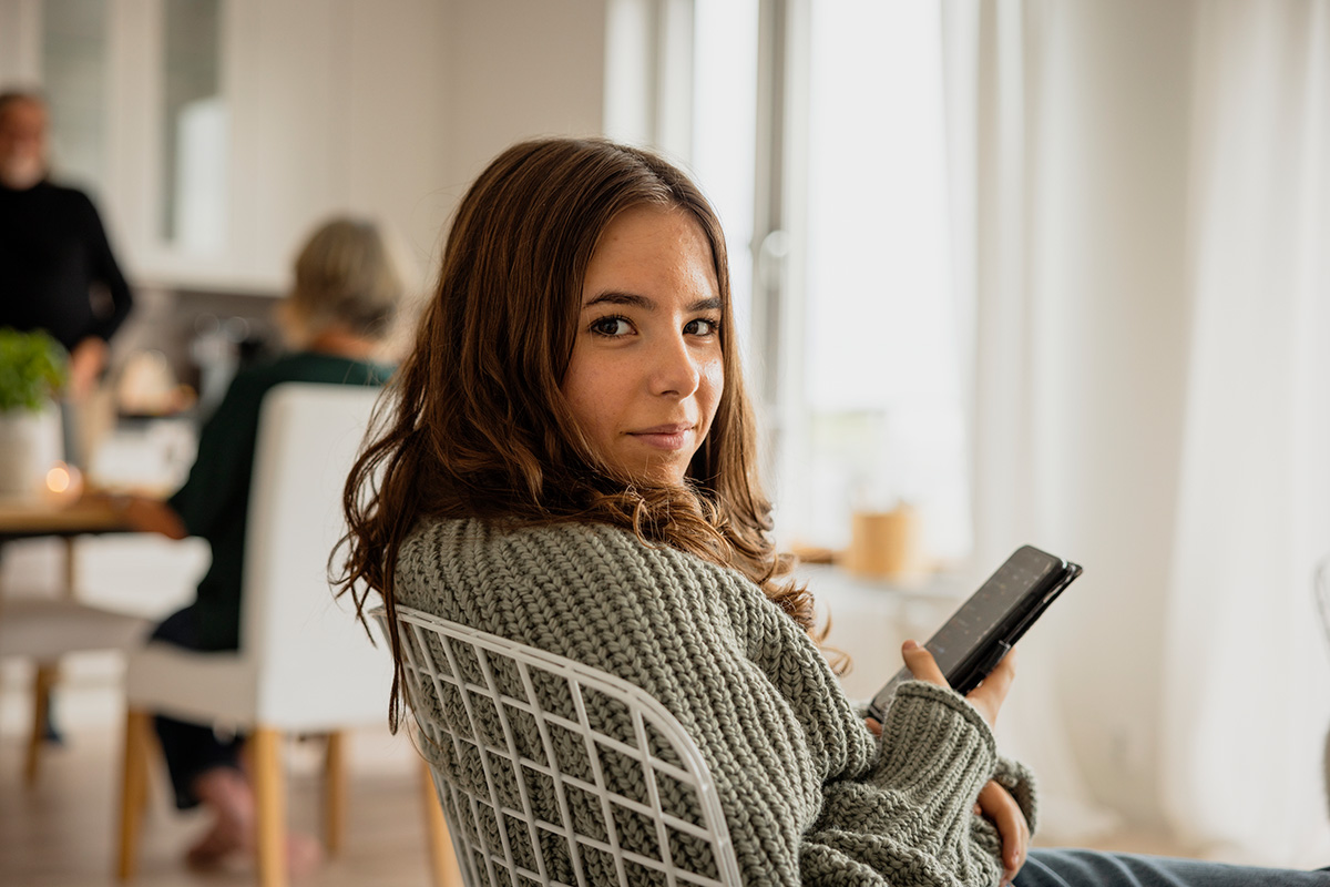 En flicka sitter i en stol och tittar i en mobiltelefon