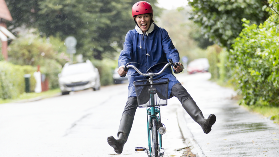 En glad kvinna sitter på en cykel.